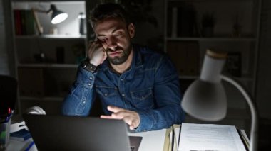 Çok çalışan ve uykulu genç İspanyol işadamı gece geç saatlerde ofis işi yaparken yakalandı. Masasında dizüstü bilgisayarla çalışırken sıkıntısını dile getiriyor.