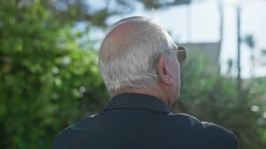 Olgun, beyaz saçlı, yaşlı bir adamın gelişigüzel portresi, yemyeşil parka bakarak, geriye dönük bir bakış, hayat yolculuğunun bir yansıması.
