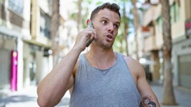 Güneşli şehir caddesinde yürürken akıllı telefondan konuşan sakallı yakışıklı adam.