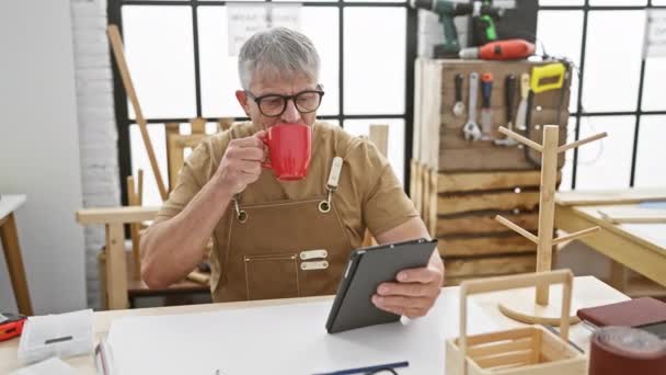 Ώριμος Άνδρας Στην Ποδιά Πίνει Καφέ Ενώ Χρησιμοποιεί Tablet Εργαστήριο — Αρχείο Βίντεο