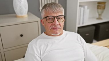 Beyaz saçlı, orta yaşlı bir adamın yatak odasında top oynaması pijamayla neşeli bir oyun oynaması. Gülümseyen yüz neşe dolu, ellerini gösteren ve neşeli ifadeler.