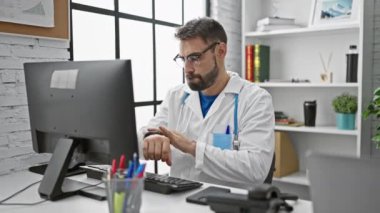 Yakışıklı, sakallı, İspanyol asıllı, klinik üniformalı ciddi bir tıp uzmanı, bir sağlık merkezinde kapalı alanda çalışıyor. Akıllı telefon kullanarak, saate bakıyor, tıkırdayan zamandan rahatsız oluyor..