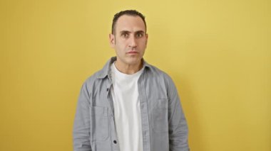Gömlek giyen yakışıklı İspanyol genç adam, kulak misafiri olmak için bir duruş sergiliyor, ağız sulandırıcı dedikoduları ya da söylentileri yakalıyor! portre sarı arkaplan üzerine kurulmuş, sağırlık konsepti taşınıyor.