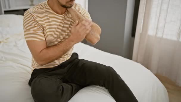Hispanic Mann Anwendung Lotion Auf Den Ellbogen Einem Gemütlichen Schlafzimmer — Stockvideo