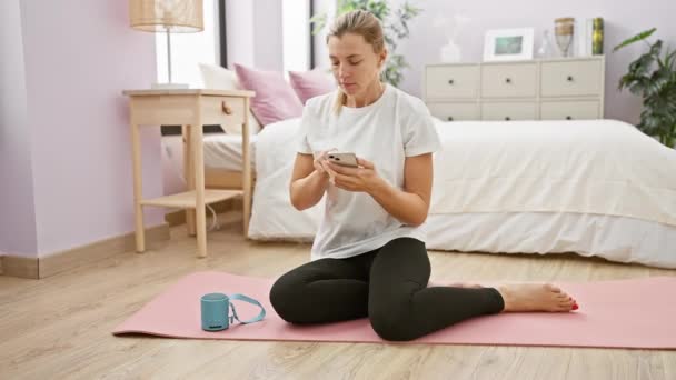 Mujer Joven Sentada Una Esterilla Yoga Dormitorio Usando Teléfono Inteligente — Vídeo de stock