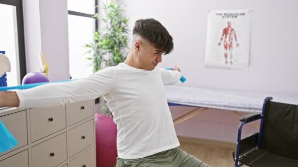 Bonito Jovem Hispânico Flexionando Seu Poder Esticando Braços Com Banda — Vídeo de Stock