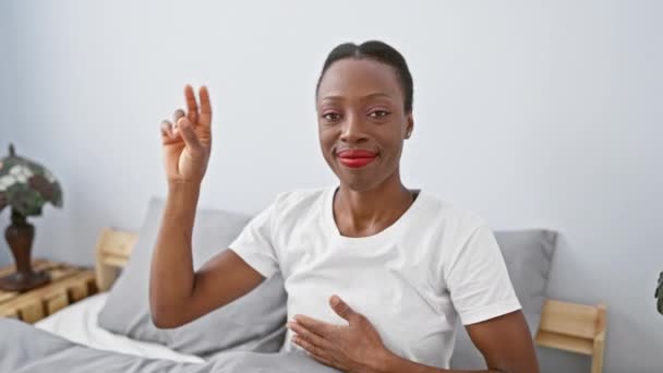 忠実で誇り高く美しいアフリカ系アメリカ人女性は 寝室のベッドで快適に横たわり 胸に手を置く厳粛な誓いを誓います — ストック動画