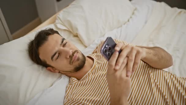 Jóképű Spanyol Férfi Mosolyog Miközben Használja Okostelefon Hálószobában Megjelenítve Pihenés — Stock videók