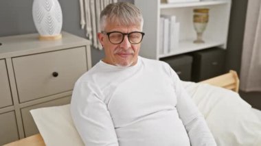 Neşeli orta yaşlı, gri saçlı, gülümseyen ve sana sıcak yatak odasından işaret ederken 