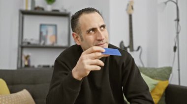 Düşünceli bir adamın elinde kredi kartı vardır. Finansı ya da online alışverişi yansıtır..