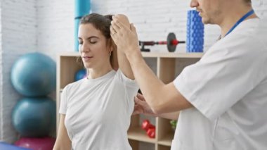 Erkek bir terapist, kadın bir hastaya parlak bir fizyoterapi kliniğinde egzersiz yaparken rehberlik eder..