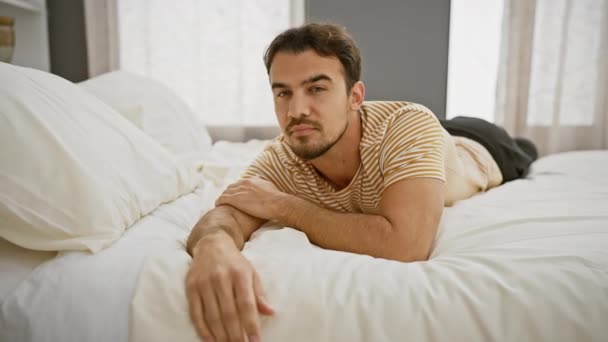 Handsome Hispanic Man Lying Thoughtfully Sunlit Bedroom Portraying Casual Relaxation — Stock Video