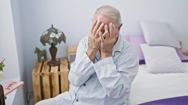 一位垂头丧气的老人 羞愧地在卧室里哭泣 一副年迈的画像 手上捂着脸 穿着睡衣 坐在床上 — 图库视频影像