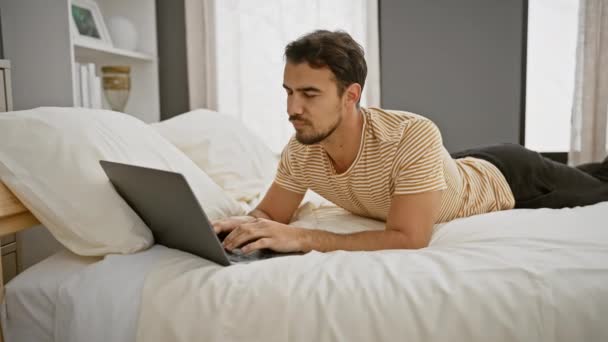 Young Hispanic Man Beard Lying Bed Working Laptop Modern Bedroom — Stock Video