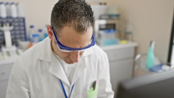 在一个设备齐全的实验室里 站着一位戴着安全护目镜 身穿实验室外套的专业人员 面对着摄像机 — 图库视频影像