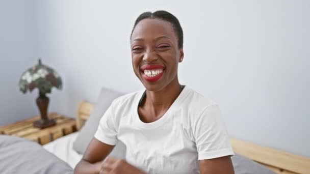 興奮したアフリカ系アメリカ人女性が寝室で怒って祝い 喜びの成功はベッドに横たわり 腕を上げました — ストック動画