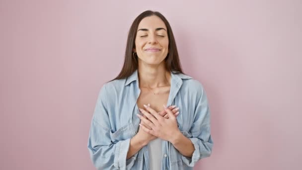 感謝の心 美しいヒスパニック女性カジュアルウェア 誠実な笑顔のジェスチャーで胸に手 ピンクの背景に健康と幸せを放射する — ストック動画