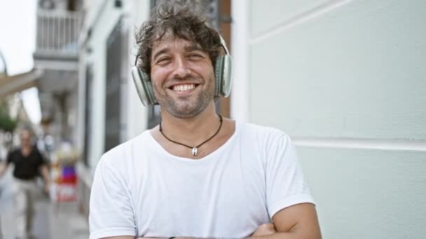 Hombre Hispano Sonriente Con Pelo Rizado Usando Auriculares Una Camiseta — Vídeo de stock