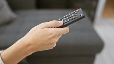 Modern bir oturma odasında televizyon kumandası tutan bir kadının yakın çekimi.
