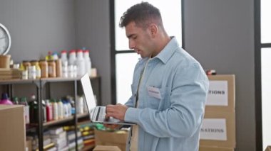 Hayır kurumunda gönüllü olarak çalışan kendini işine adamış genç İspanyol bir adam. Toplum ambarının kalbindeki laptoptan bağış ürünlerini kontrol ediyor.