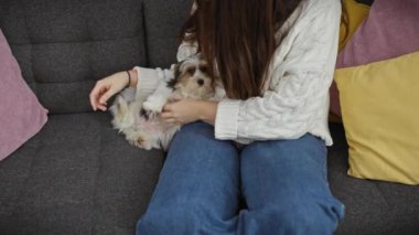 Gündelik giyinmiş genç bir kadın, bisiklet teriyeri ile sessiz bir anın tadını çıkarıyor. İçerideki rahat koltukta, renkli yastıklarla çevrili..