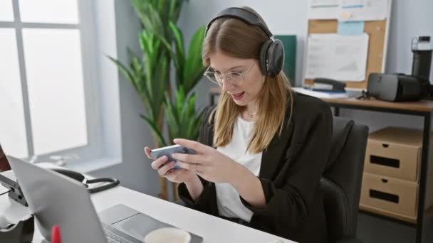 Μια Νεαρή Γυναίκα Ακουστικά Χρησιμοποιώντας Smartphone Μια Σύγχρονη Ρύθμιση Γραφείου — Αρχείο Βίντεο