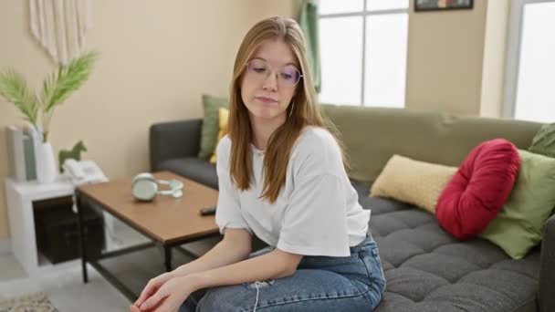 一位神智清醒 戴眼镜的年轻的高加索女人坐在自家客厅里 — 图库视频影像