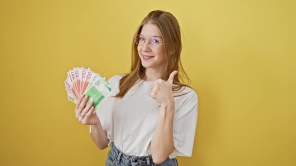 Веселая Молодая Женщина Показывает Норвежскую Валюту Жёлтом Фоне Выражая Позитивность — стоковое видео
