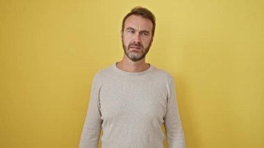 Sersemlemiş İspanyol bir adam, sarı izole edilmiş arka planda el ele dururken, 'Tüh!' diyerek aptalca bir hata yaptığı için hemen pişman olur. Kayıyor - oh, hatalı bir hafızanın ahmaklığı!