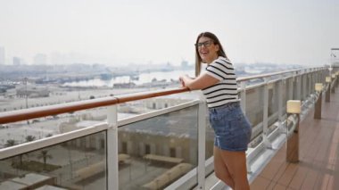 Yolcu gemisine yaslanan genç bir kadın deniz manzarasının keyfini çıkarıyor ve açık mavi gökyüzü ile seyahat ediyor..