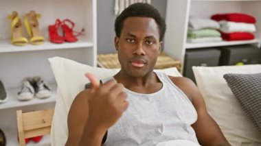 Yatak odasında, pijamalı Afro-Amerikalı genç bir adamın ağzı açık bir şekilde şaşkınlık ve şaşkınlık içinde yüzünü gösterdiğini görmek hayret verici.