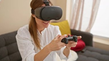 Modern bir oturma odasında VR kulaklık takan beyaz bir kadın.