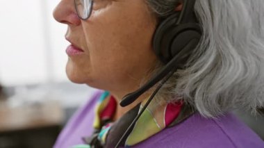 Modern ofis içinde kulaklığı, gözlüğü, gri saçı, konuşması, odaklanması, işi, desteği olan profesyonel son sınıf öğrencisi bir kadın.