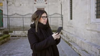 Genç bir kadın tarihi İstanbul 'u keşfederken, seyahat, kültür, teknoloji, eğlence, gözlük, turizm, şehir, Avrupa, fotoğrafçılık ve yetişkinleri somutlaştırırken akıllı telefon kullanıyor..