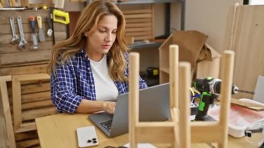 Şaşırmış genç Latin bir kadın, ağzı açık, marangozluk masasının ilerisini işaret ediyor, güzel dışavurumcu yüzü içeride inanılmaz bir şey keşfediyor.