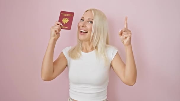 エキサイティングな若いブロンドの女性 ナンバーワンのスマーティ 自信を持って笑顔で彼女のアイデアを指摘し ピンクの孤立した背景上のパスポート — ストック動画
