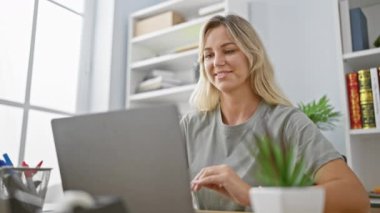 Modern ofiste kitaplığı ve bitkisi olan gülümseyen bir kadın.