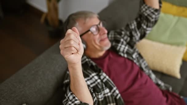 Veselý Šedovlasý Muž Smějícími Brýlemi Gauči Útulném Interiéru — Stock video