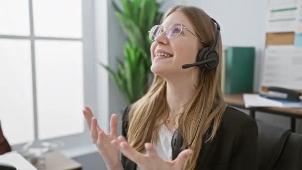 一个快乐的年轻女人 头戴耳机 在现代化的办公室里庆祝成功 — 图库视频影像
