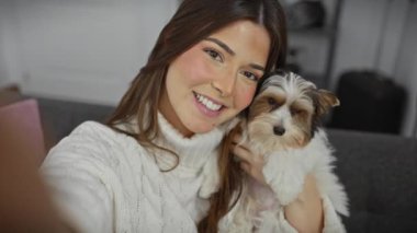 Sıcak bir oturma odasında bisikletli teriyeri şefkatle tutan gülümseyen genç bir kadın.