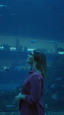 Genç bir kadın Dubai 'deki bir su altı akvaryumunda deniz yaşamını gözlemliyor, seyahat ve turizm sergiliyor..