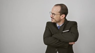 Gözlüklü, takım elbiseli, beyaz arka planda duran gülümseyen profesyonel bir adam.