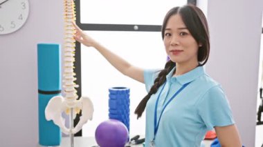 Omurga modeli olan Çinli kadın fizyoterapist klinikte.