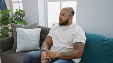 Afrika kökenli Amerikalı bir adam yoğun bir öfkeyle, çılgın bir öfkeyle koltukta otururken öfkesini haykırıyor, kollarını kaldırıyor - evinin rahatlığından dolayı üzgün bir ifade.