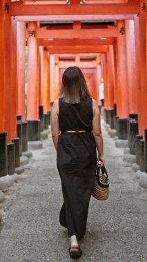 Güzel gözlüklü İspanyol bir kadın Fushimi 'nin Torii Kapısı' nda gelişigüzel bir yürüyüşü kucaklıyor, Kyoto yolun maneviyatını hissediyor.