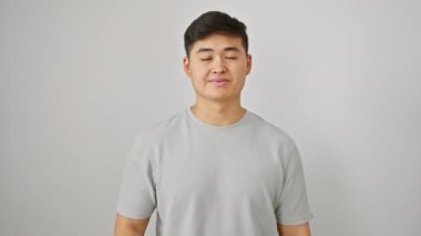 Mutlu genç Çinli adam mükemmel bir onay işareti veriyor, özgüvenle gülümsüyor ve izole edilmiş bir arka planda serin beyaz tişörtle duruyor.