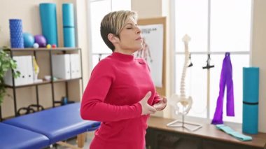 Pembe kazaklı kısa sarı saçlı İspanyol kadın bir rehabilitasyon kliniğinde meditasyon yapıyor..