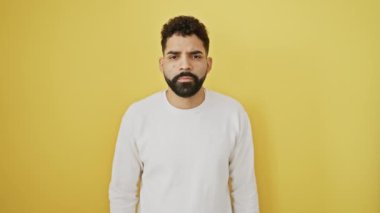 Sarı üzerine öfkeli genç bir adam, boğazı kesilmiş bir jesti eliyle taklit ederek şiddeti tehdit ediyor, izole bir ortamda saldırganlığı kapsıyor gibi.