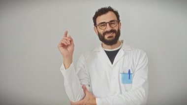 Neşeli orta yaşlı bir adam, bilim adamı üniforması içinde, beyaz bir arka planda izole edilmiş, sırıtışıyla kenarı işaret ediyor.