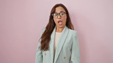 İş ceketinde şüpheci İspanyol güzeli, genç kadın, ağzı tamamen açık inançsız, pembe izole edilmiş arka planda alaycı bir bakış atıyor..